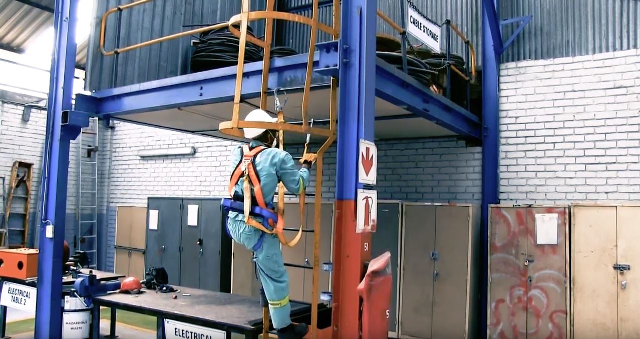 man wearing safety harness climbing ladder
